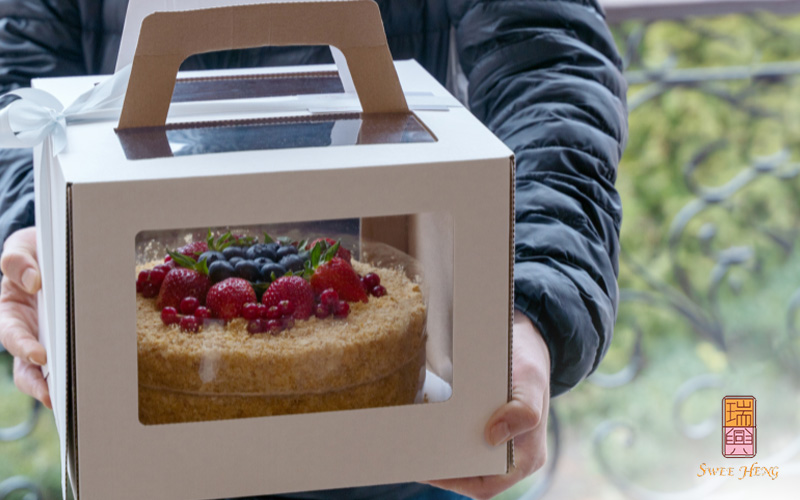 A man delivering a box of cake decorated with berries