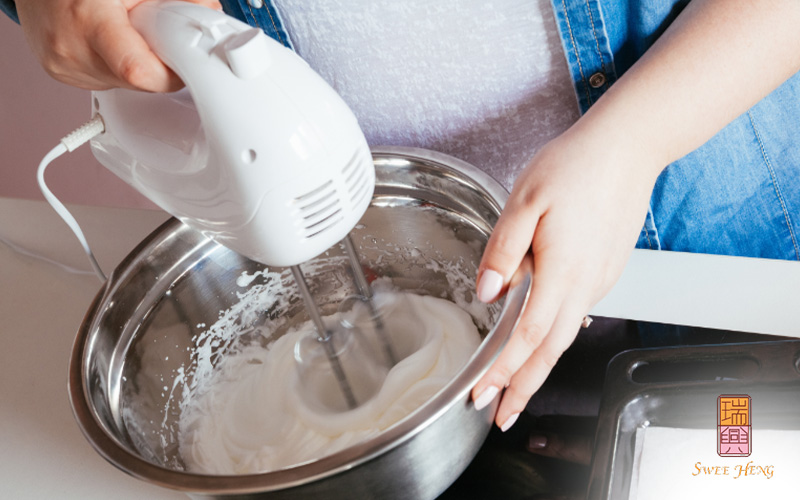 Baker mixing cake batter with an electric hand mixer