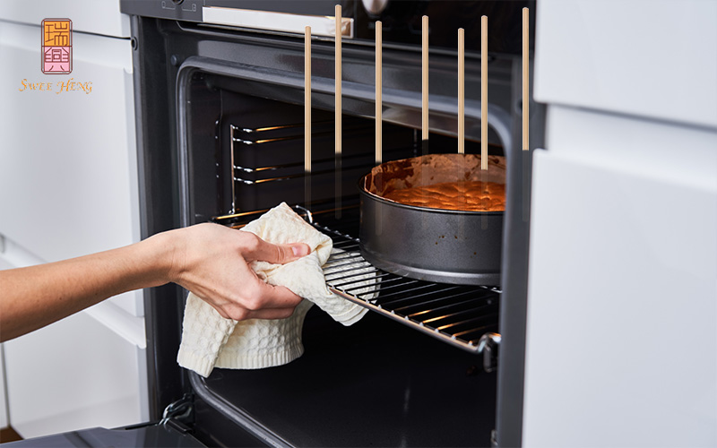 A baker putting a cake in the oven