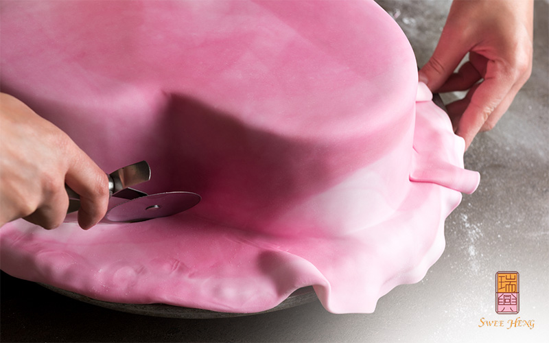 Decorating heart-shaped wedding cake with pink fondant