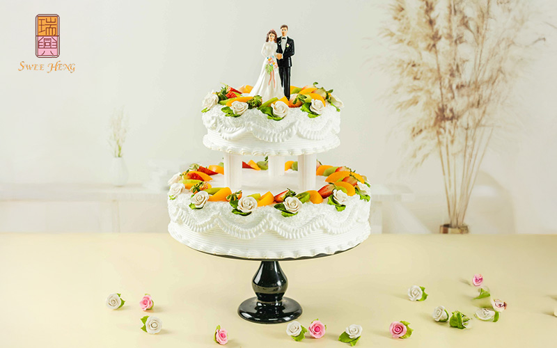 Elegant 2-tiered wedding cake adorned with bride and groom figurine topper